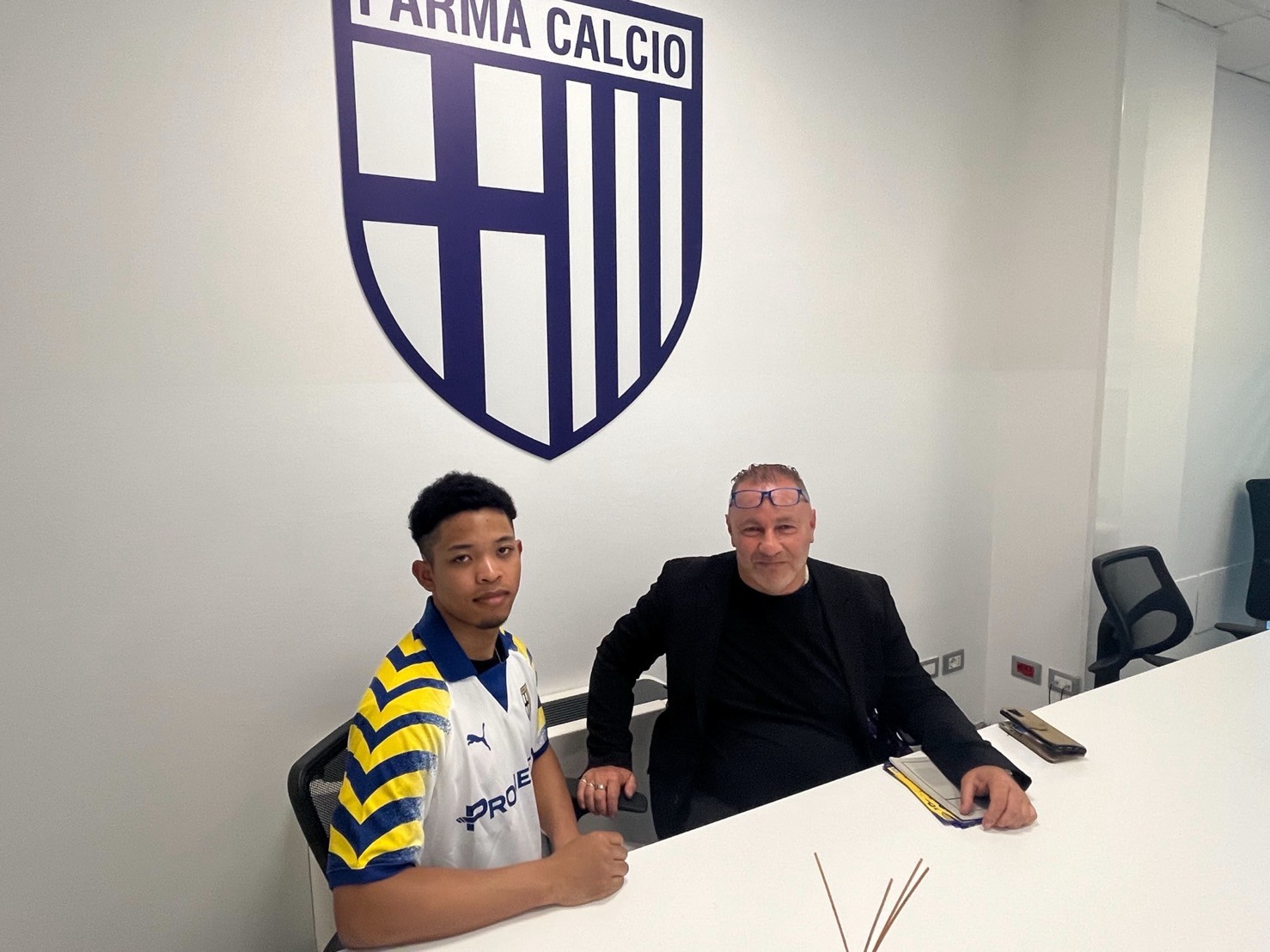 PARMA CALCIOのエンブレムがある室内で並んで座る二人